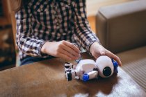 Abgeschnittenes Bild eines Mädchens, das das Roboterspielzeug zu Hause repariert — Stockfoto
