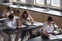 Teacher assisting students in experiment at laboratory — Stock Photo
