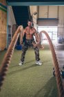 Визначений м'язистий чоловік тренується з мотузкою у фітнес-студії — стокове фото