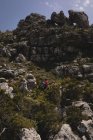 Wanderer klettert an einem sonnigen Tag mit Rucksack den Berg hinauf — Stockfoto