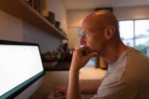 Чоловік працює на персональному комп'ютері вдома, вид збоку . — стокове фото