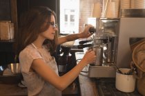 Barista al vapor de leche en la máquina de café en un café - foto de stock