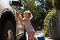 Дівчина миє машину в гаражі в сонячний день — стокове фото