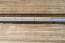 Antenne der leeren Straße, die durch Weizenfeld führt — Stockfoto