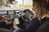Schöne weibliche Führungskraft mit Handy während des Autofahrens — Stockfoto