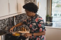 Жінка готує їжу на сковороді на плиті на кухні . — стокове фото