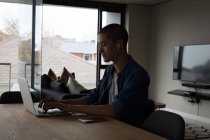 Junger Mann hört Musik, während er zu Hause Laptop benutzt — Stockfoto