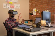 Executivo masculino usando fone de ouvido de realidade virtual na mesa no escritório — Fotografia de Stock