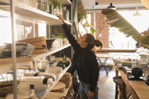 Женщина кладет банку на полку в кофейне — стоковое фото