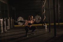 Молода жінка піднімається з барбелом у спортзалі — стокове фото