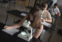 Estudiantes universitarios experimentando con microscopio en laboratorio en la universidad - foto de stock