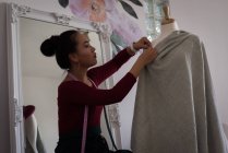 Stilista di moda pinning tessuto sul manichino in studio di design . — Foto stock