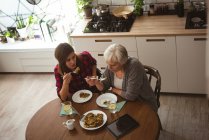Високий кут зору старшої жінки і дочки їдять омлет на кухні на сніданок — стокове фото