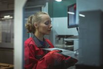 Travailleur féminin vérifiant une planche de machine dans l'usine — Photo de stock