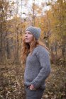 Mulher bonita em roupas quentes em pé na floresta de outono — Fotografia de Stock