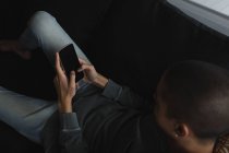 Молодий чоловік використовує мобільний телефон у вітальні вдома — стокове фото
