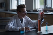 Хлопчик-підліток експериментує з хімічним розчином в лабораторії — стокове фото