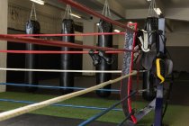 Punching bags and boxing equipment on boxing ring in fitness studio. — Stock Photo