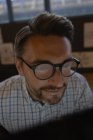 Крупный план мужчины в очках, работающего за компьютером в офисе . — стоковое фото
