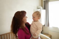 Mother holding her baby girl in bedroom at home — Stock Photo