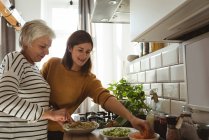 Seniorin und Tochter kochen zu Hause gemeinsam in der Küche — Stockfoto