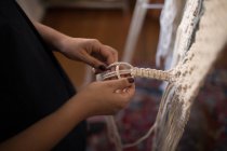 Mid section of woman knotting strings in workshop — Stock Photo