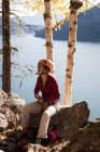 Bergsteiger sitzt auf Felsen am Seeufer — Stockfoto