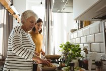 Senior woman and daughter preparing salad in the kitchen — Stock Photo