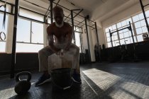 Senior man rubbing white powder on hands before workout in fitness studio. — Stock Photo