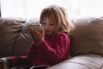 Girl using mobile phone in living room at home — Stock Photo
