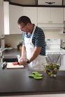 Homem de corte de tomate em tábua de corte com faca na cozinha — Fotografia de Stock