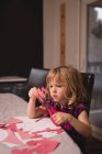 Mädchen bereitet Dekoration in Herzform zu Hause mit Bastelpapier vor — Stockfoto
