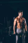Мускулистый мужчина тренируется с гантелями в фитнес-студии — стоковое фото