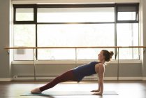 Жінка практикує йогу на тренувальному килимку у фітнес-студії . — стокове фото