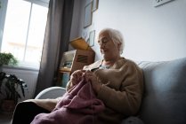 Seniorin strickt Wolle im heimischen Wohnzimmer — Stockfoto