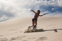 Sandboard femme sur dune de sable au désert — Photo de stock