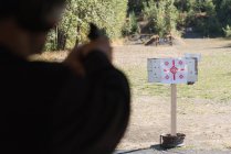 Mid section of man aiming gun at target in shooting range — Stock Photo