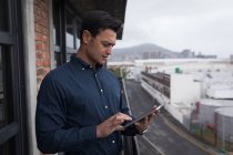 Бизнесмен с помощью цифрового планшета на балконе в офисе . — стоковое фото