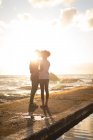 Романтична пара стоїть на дрібниці під час заходу сонця — стокове фото