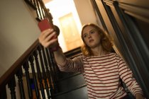 Mujer tomando una selfie en la escalera en casa - foto de stock