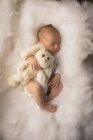 Newborn baby sleeping with rabbit plush toy on fluffy blanket. — Stock Photo