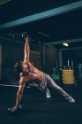 Мускулистый человек делает отжимания с гантелями в фитнес-студии — стоковое фото