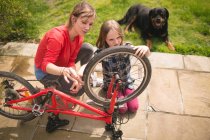 Мати і дочка ремонтують велосипед разом на задньому дворі — стокове фото