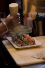 Chef adicionando molho de mostarda sobre sushi no balcão da cozinha — Fotografia de Stock
