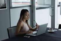 Азиатская бизнесвумен сидит на стуле и работает над ноутбуком в офисе — стоковое фото