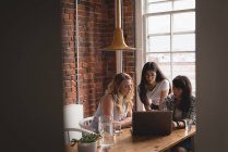 Женщины-руководители обсуждают за ноутбуком друг с другом в креативном офисе — стоковое фото