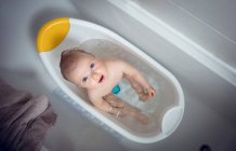 Bébé fille prenant bain dans la baignoire à la salle de bain — Photo de stock