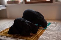 Madre e hija musulmana rezando salah en casa - foto de stock
