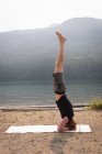 Side view of sporty man practicing head stand near the sea coast — Stock Photo