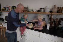Отец с детьми готовит еду на кухне дома . — стоковое фото